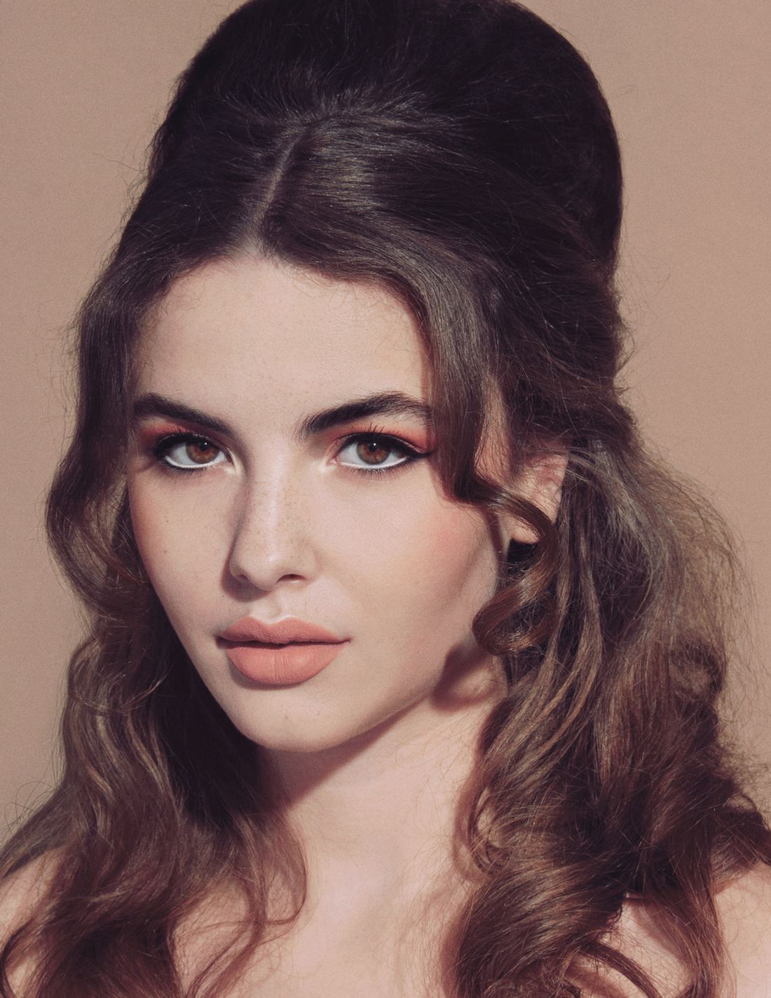 Glam make-up met warme oogschaduw, eyeliner en volumineus haar