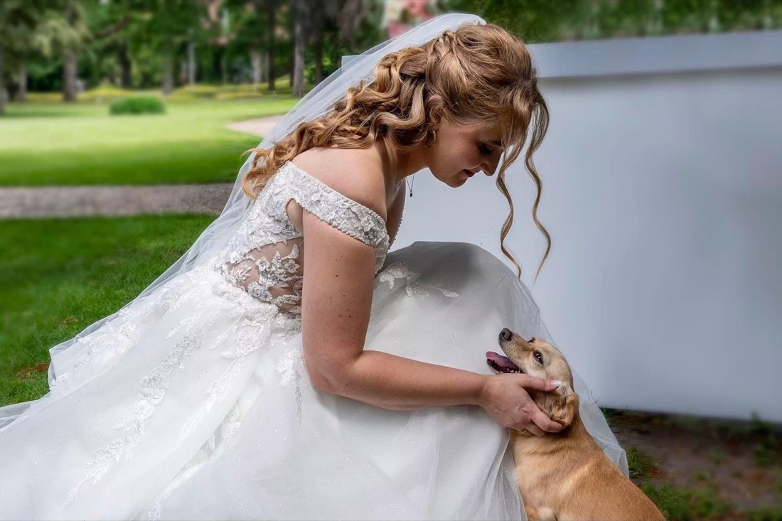 Cheryl in haar trouwjurk met krullen en sluier, met haar hond